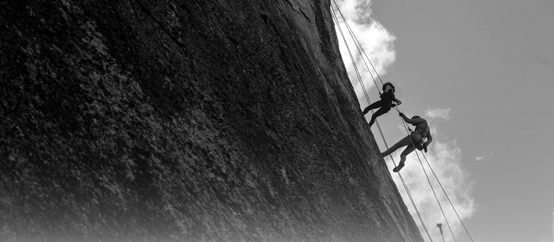 Climbers scaling a cliff, symbolizing the shift from projected growth to proven outcomes.