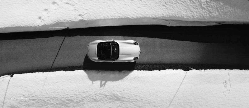 A sports car driving through a narrow snow-lined road, symbolizing focus, speed, and strategic navigation in public markets.