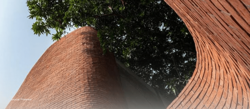 Curved brick walls beneath trees evoking growth beyond metros and the rise of Tier II and III HNI capital.
