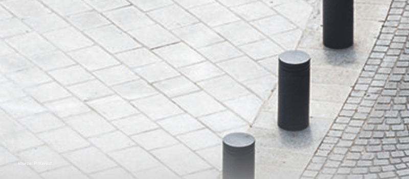 Aligned bollards on a tiled walkway representing intelligent, risk-managed alternative allocations.
