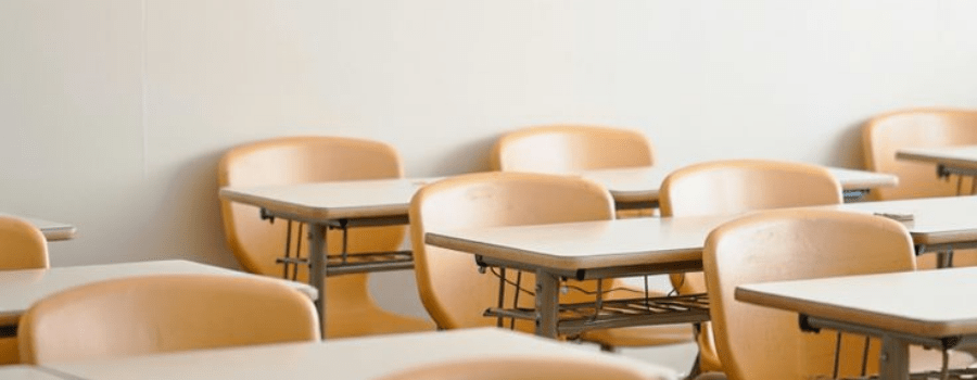 Empty classroom desks, representing private equity's move into K-12 school ownership